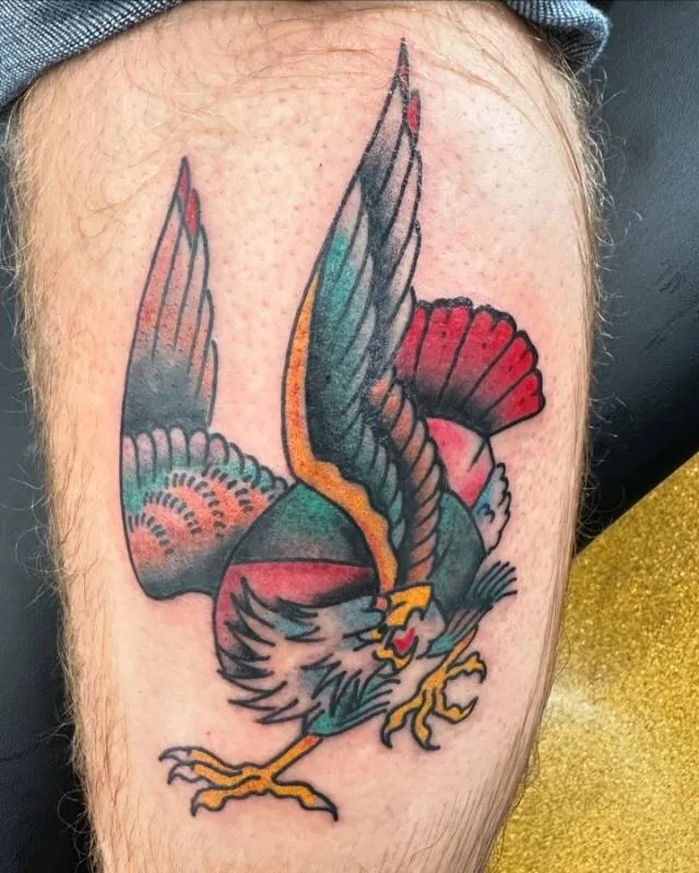 American Traditional color tattoo of a bald eagle mid-flap with a Spam musubi as its body — wings spread, talons forward, classic Hawaiian-American mash-up — on the thigh, by Julian (xwildxlovex) at Ohana Tattoo Company, Waikiki, Hawaii.
